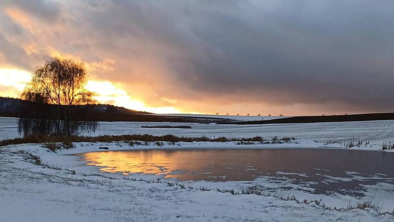 Wolkenhimmel im Abendrot über der verschneiten Landschaft am Katharinenberg
